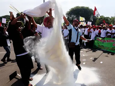 Petani tebu melakukan aksi menebar gula rafinasi saat unjuk rasa di depan Istana Merdeka, Jakarta, Senin (28/8). Aksi itu bentuk ungkapan kekecewaan terhadap sikap pemerintah yang masih membiarkan gula impor merembes di pasaran (Liputan6.com/Angga Yuniar)