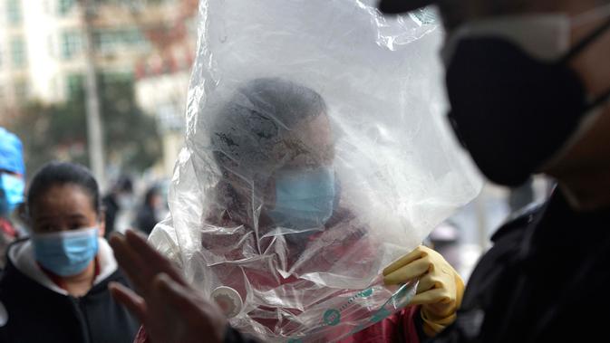 Seorang pria bermasker menutupi dirinya dengan plastik untuk melindungi diri dari wabah virus corona sebelum memasuki sebuah supermarket di Wuhan China, 10 Februari 2020. WHO mengatakan wabah virus corona COVID-19 merupakan ancaman sangat besar bagi seluruh dunia. (Chinatopix via AP)