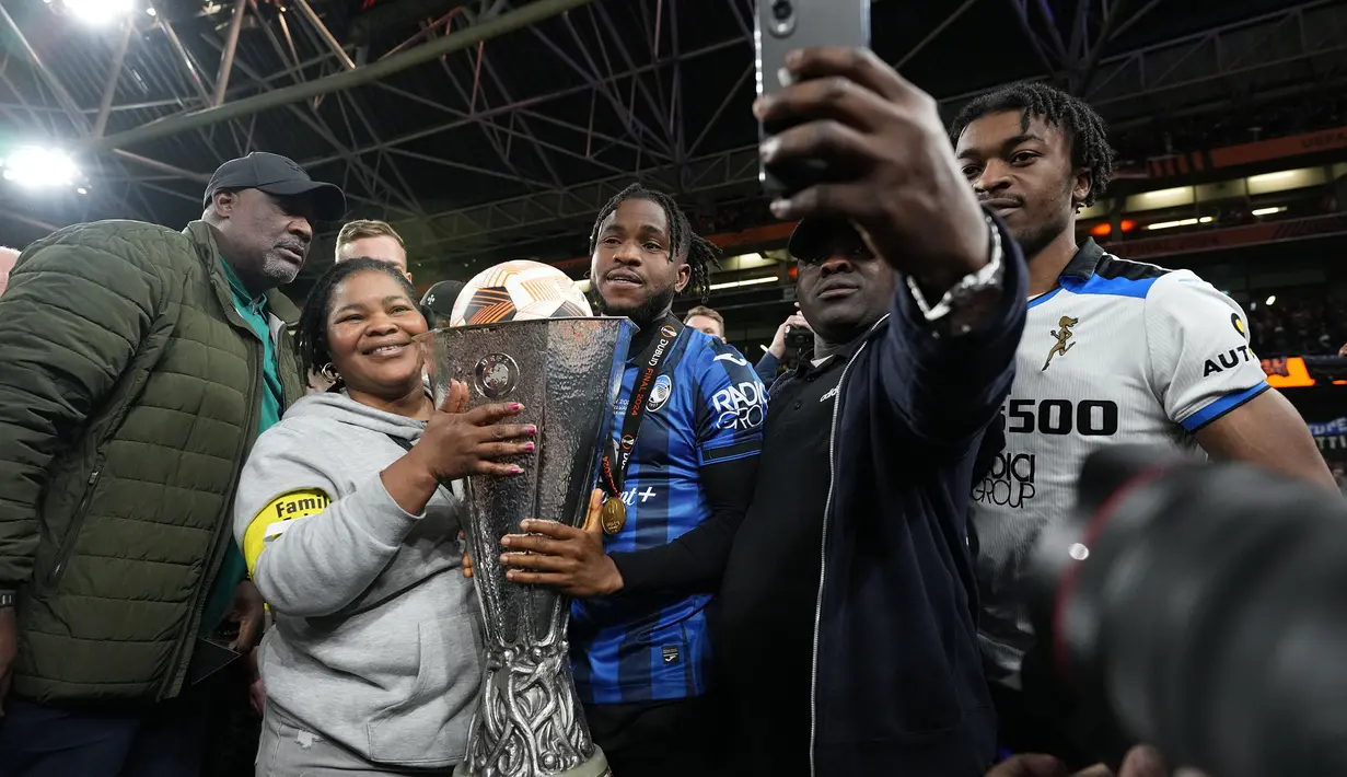 Pemain Atalanta, Ademola Lookman (tengah) bersama keluarganya melakukan swafoto saat merayakan gelar juara Liga Europa 2023/2024 setelah mengalahkan Bayer Leverkusen di laga final yang berlangsung di Dublin Arena, Irlandia, Kamis (23/05/2024) dini hari WIB. (AP Photo/Kirsty Wigglesworth)