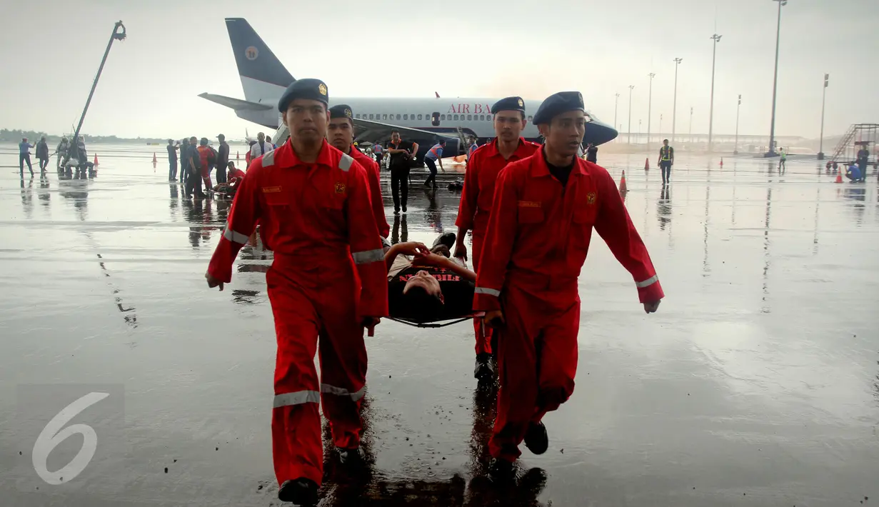 Petugas menggotong seorang korban dalam kegiatan menghadapi keadaan darurat di landasan terminal 3 Bandara Soekarno - Hatta, Tangerang, Kamis, (25/2). Pelatihan simulasi ini diikuti 900 peserta. (Liputan6.com/Faisal R Syam)