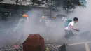 Pengunjuk rasa menghindari gas air mata yang ditembakan oleh polisi anti huru hara di luar gedung Dewan Legislatif, Hong Kong, Rabu (12/6/2019). Bentrok diawali ketika para pengunjuk rasa merangsek melewati garis polisi dan memaksa masuk ke gedung Dewan Legislatif. (AP Photo/Kin Cheung)