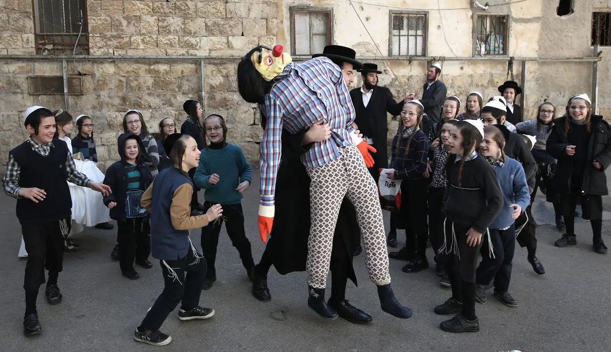 Seorang pria membawa boneka yang melambangkan figur Haman untuk perayaan purim di Yerusalem (8/3). Perayaan ini sebagai bentuk peringatan orang Yahudi bebas dari rencana jahat Haman. (AFP/Menahem Kahana)