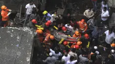 Petugas membawa korban yang selamat dari puing-puing bangunan tempat tinggal tiga lantai yang runtuh di Bhiwandi, India, Senin (21/9/2020). Sepuluh orang tewas dan sekitar 25 lainnya dikhawatirkan masih terjebak setelah bangunan itu runtuh sebelum fajar saat para penghuni terlelap tidur. (AFP)
