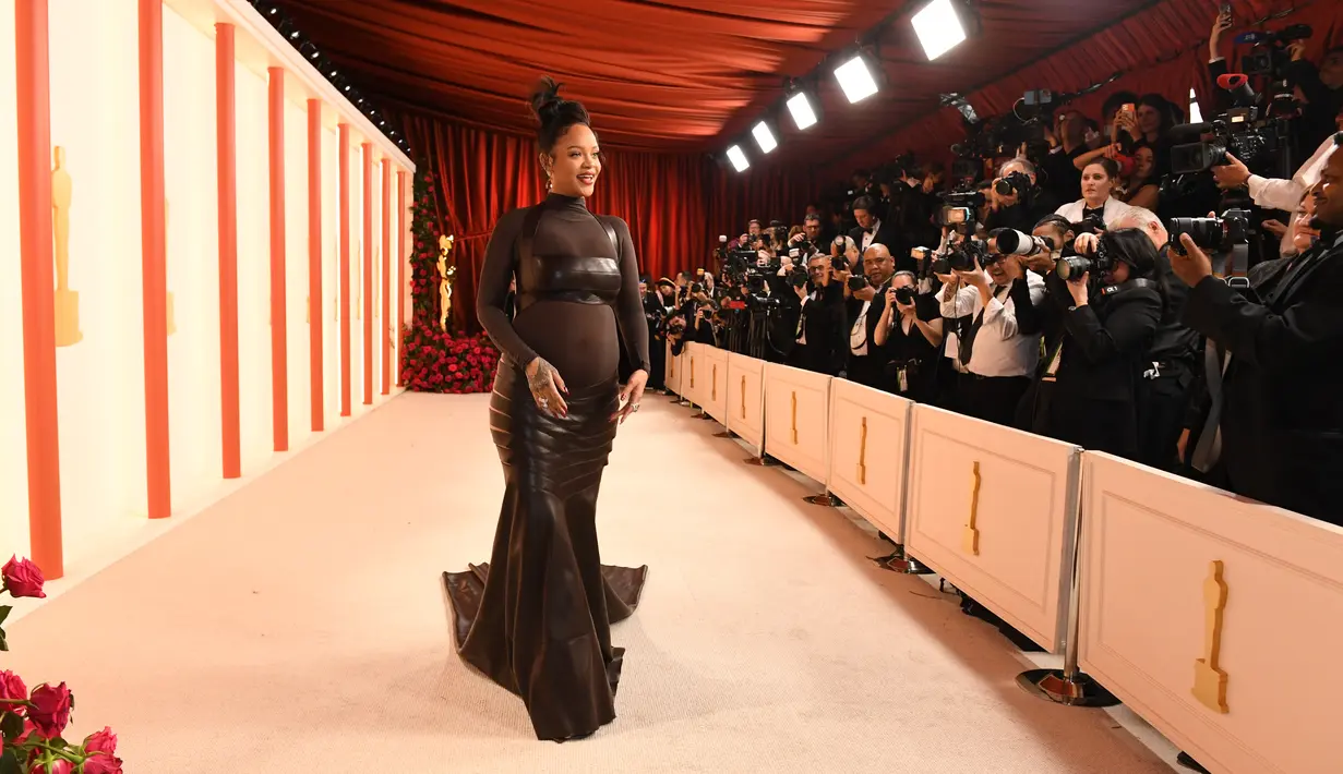 Penyanyi/aktris Barbados Rihanna menghadiri Academy Awards ke-95 atau Oscar 2023 di Teater Dolby di Hollywood, California pada Minggu, 12 Maret 2023, waktu setempat. Pelantun "Where Have You Been" ini berbalut gaun ikat kulit dari Alaïa yang dibuat khusus sembari memamerkan baby bump. (Photo by VALERIE MACON / AFP)