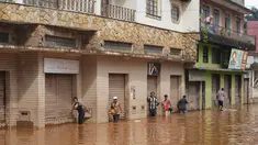 Orang-orang berjalan di jalan yang banjir di Raposos, negara bagian Minas Gerais, Brasil, Selasa (11/1/2022). Tanah longsor akibat hujan deras telah menewaskan sedikitnya 12 orang dan pihak berwenang sedang memantau bendungan yang bisa jebol. (AP Photo/Eugenio Savio)