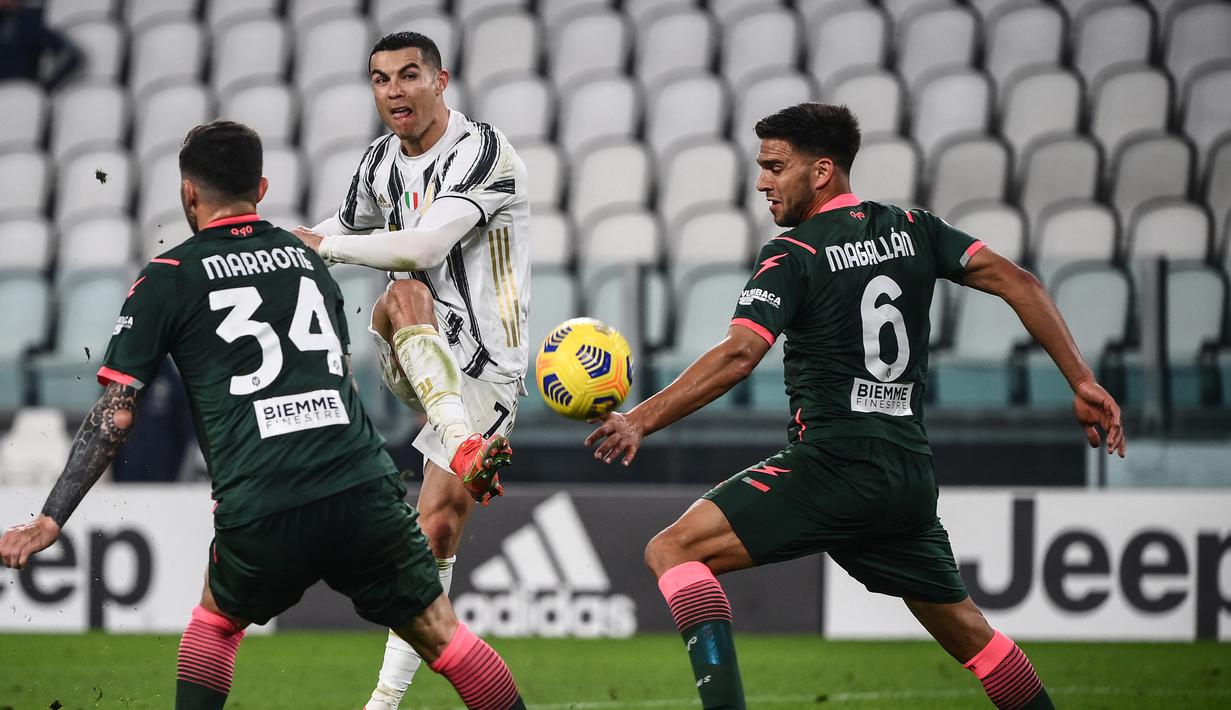 Bintang Juventus, Cristiano Ronaldo melakukan tendangan di antara pemain Crotone Luca Marrone dan Lisandro Magallan dalam lanjutan Liga Italia di Allianz Stadium, Selasa dinihari WIB (23/2/2021). Ronaldo menyumbang dua gol pada laga ini, satu gol lagi disumbang Weston McKennie (Marco BERTORELLO/AFP)