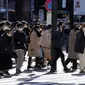 Warga yang memakai masker untuk membantu mengekang penyebaran COVID-19 menyeberang jalan di Tokyo, Jepang, 21 Januari 2022. Jepang memperluas pembatasan COVID-19 karena varian Omicron yang menyebabkan kasus melonjak ke level tertinggi baru di wilayah metropolitan. (AP Photo/Eugene Hoshiko)