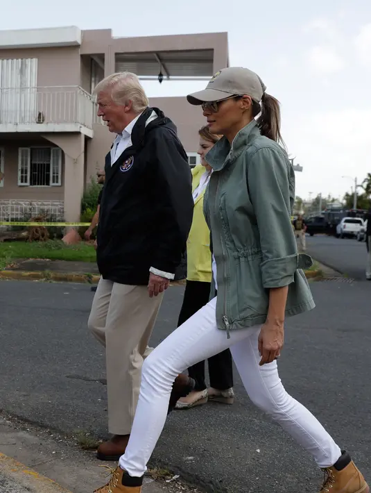 Presiden AS Donald Trump dan ibu negara Melania Trump berkeliling ke permukiman yang terdampak Badai Maria di Guaynabo, Puerto Rico, Selasa (3/10). Melania dikritik lantaran jins putih dinilai tidak praktis karena sangat mudah kotor. (AP Photo/Evan Vucci)