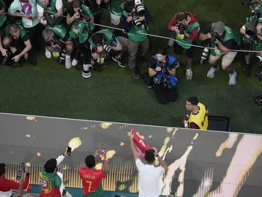Fotografer memotret Cristiano Ronaldo saat berjalan ke bangku timnya pada awal pertandingan babak 16 besar Piala Dunia antara Portugal dan Swiss, di Stadion Lusail di Lusail, Qatar, Selasa (6/12/2022). Ronaldo mengawali laga dari bangku cadangan. Dia baru masuk menggantikan Joao Felix pada menit 73 ketika Portugal sudah unggul 5-1. (AP Photo/Thanassis Stavrakis)