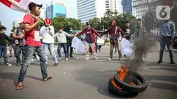 Massa Himpunan Mahasiswa Islam (HMI) membakar ban bekas saat berunjuk rasa menentang UU Cipta Kerja di kawasan Patung Kuda, Jakarta, Rabu (28/10/2020). Massa meminta Presiden Joko Widodo segera mencabut UU Cipta Kerja melalui Peraturan Pemerintah Pengganti Undang-Undang. (Liputan6.com/Faizal Fanani)