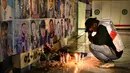 Seorang pria berduka di depan tugu peringatan dengan potret para korban di dinding sebelum doa pada peringatan satu tahun tragedi terburuk dalam sejarah sepak bola Indonesia di stadion Kanjuruhan Malang, Jawa Timur, pada 1 Oktober 2023. (Juni Kriswanto/AFP)