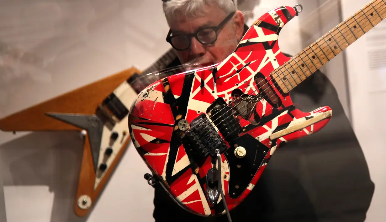 Seorang pria memeriksa gitar yang dibuat dan dimainkan oleh Eddie Van Halen selama pratinjau pers pameran Play It Loud: Instruments of Rock & Roll di Metropolitan Museum of Art di New York, 1 April 2019. Koleksi instrumen di pameran ini punya rentang usia dari 1939 hingga 2017. (AP/Seth Wenig)