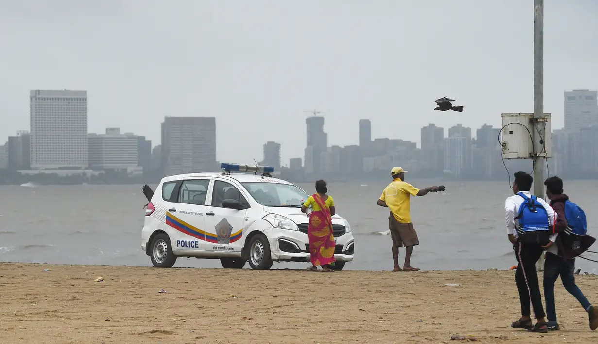 Mobil polisi terparkir di pantai Girgaum Chowpatty saat awan gelap menyelimuti langit Mumbai (12/6/2019). Badai siklon vayu melesat ke arah barat India telah diperkuat dengan hembusan angin hingga 170 kilometer per jam (105 mph) yang  akan menerjang pada 13 Juni 2019. (AFP Photo/Punit Paranjpe)