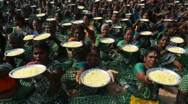 Para wanita membawa bunga persembahan dalam upacara penghormatan untuk korban tsunami tahun 2004 di Pantai Pattinapakkam, Chennai, India, Rabu (26/12). Lebih dari 10 ribu warga India tewas dalam tsunami Samudra Hindia pada 2004 lalu. (ARUN SANKAR/AFP)