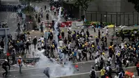 Pengunjuk rasa menghindari gas air mata yang ditembakan oleh polisi anti huru hara di luar gedung Dewan Legislatif, Hong Kong, Rabu (12/6/2019). Polisi Hong Kong telah menggunakan gas air mata ke arah ribuan demonstran yang menentang RUU ekstradisi yang sangat kontroversial. (AP Photo/Vincent Yu)