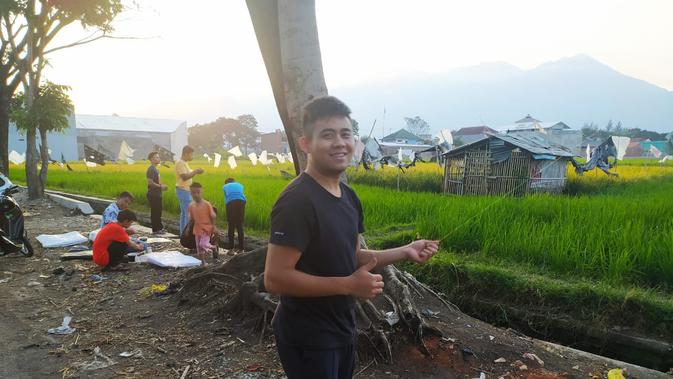 Vicky, salah satu pehobi layangan, nampak tersenyum sambil menari benang layangan yang tengah ia mainkan bersama warga lainnya di Garut, Jawa Barat. (Liputan6.com/Jayadi Supriadin)