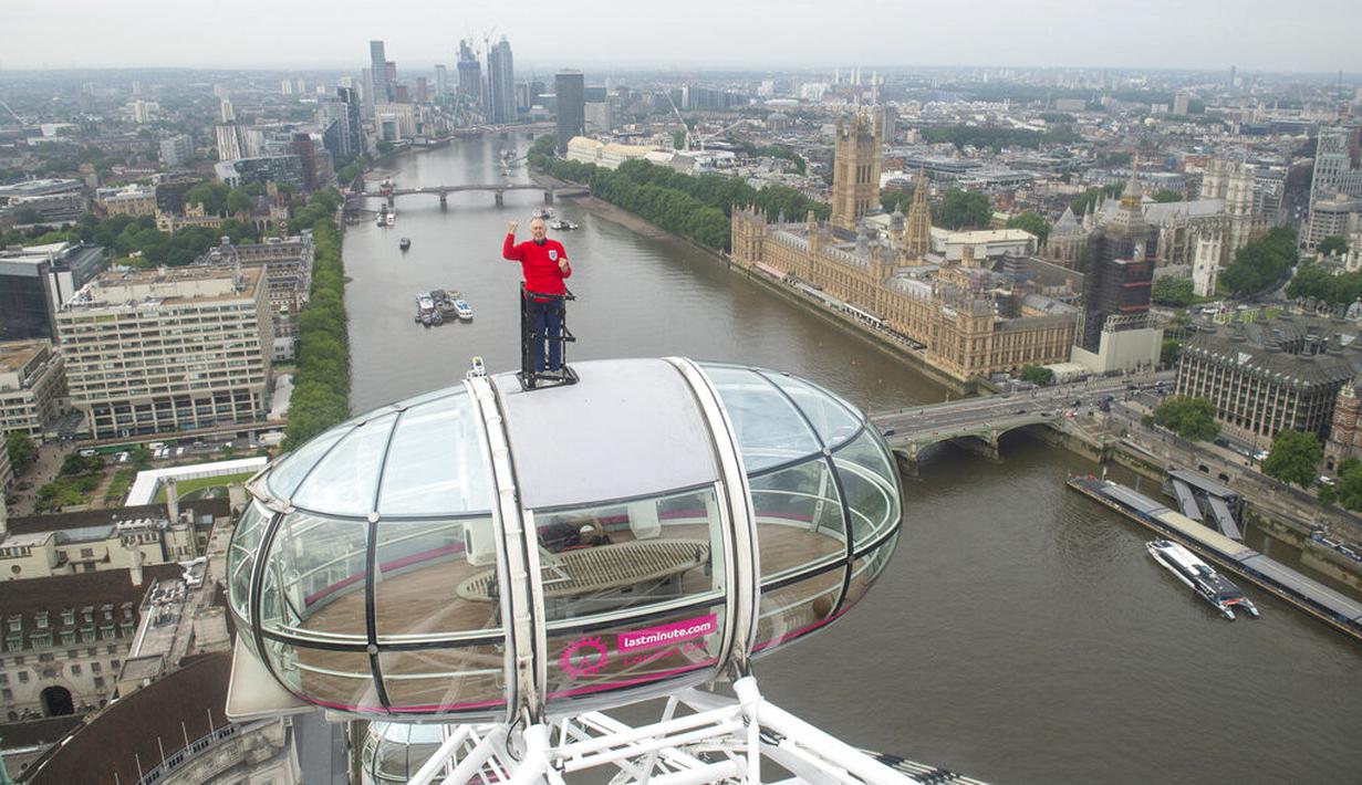 Legenda Inggris Geoff Hurst mengenakan jersey Inggris di final Piala Dunia 1966 berdiri di atas pod komedi putar London Eye memandang ke arah Stadion Wembley di London (9/7/2021). Aksi Geoff Hurst ini demi mendukung timnas Inggris melawan Italia jelang final Euro 2020. (Dominic Lipinski/PA via AP)