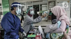 Petugas paramedis memeriksa suhu tubuh seorang ibu sebelum mengantarkan anaknya mengikuti imunisasi di Puskesmas Kecamatan Jatinegara, Jakarta, Kamis (26/11/2020). (merdeka.com/Iqbal S. Nugroho)