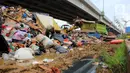 Petugas PPSU DKI Jakarta menggunakan alat berat saat mengangkut sampah sisa banjir di bawah Tol Becakayu, Cipinang Melayu, Jakarta Timur, Rabu (8/1/2020). Sampah sisa banjir tersebut selanjutnya diangkut ke TPA Bantar Gebang. (merdeka.com/Magang/Muhammad Fayyadh)