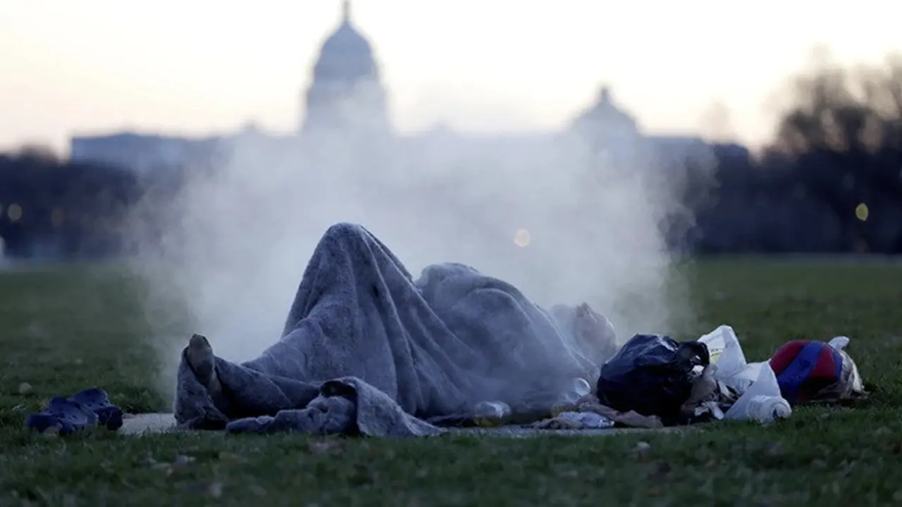 Gedung Capitol menjadi latar seorang gelandangan yang beristirahat di atas lubang uap di National Mall di kawasan Capitol Hill, Washington, DC, Amerika Serikat, pada 18 Desember 2019.