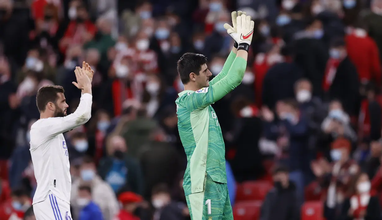 Kiper Real Madrid, Thibaut Courtois (kanan) menyapa pendukungnya usai pertandingan melawan Athletic Bilbao pada pertandingan La Liga Spanyol di stadion San Mames, Spanyol, Kamis (23/12/2021). Madrid menang atas Bilbao 2-1. (AP Photo/Ricardo Larreina)