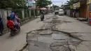 Warga melewati jalan yang rusak parah di Jalan Raya Tanjung Pasir, Tangerang, Banten, Rabu (22/1/2025). (merdeka.com/Arie Basuki)
