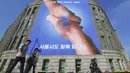 Pejalan kaki berjalan melewati spanduk yang menunjukkan foto dua tangan bersalaman dengan gambar peta Semenanjung Korea di Seoul, Korea Selatan (18/4). Spanduk ini bertujuan untuk mendukung pertemuan antara Korut dan Koresel. (AFP Photo/Jung Yeon-je)
