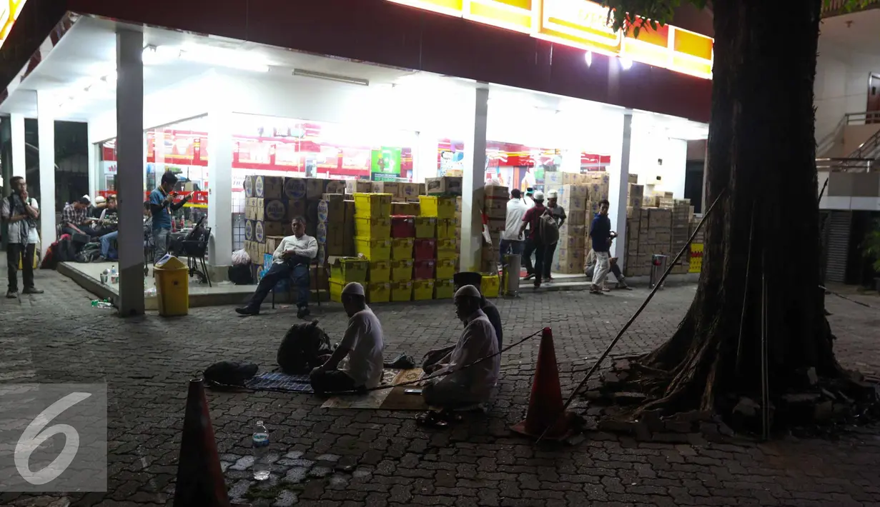 Sejumlah peserta Aksi Damai 4 November melaksanakan Salat Magrib berjamaah di depan mini market di Stasiun Gambir, Jakarta, Jumat (4/11). (Liputan6.com/Faizal Fanani)