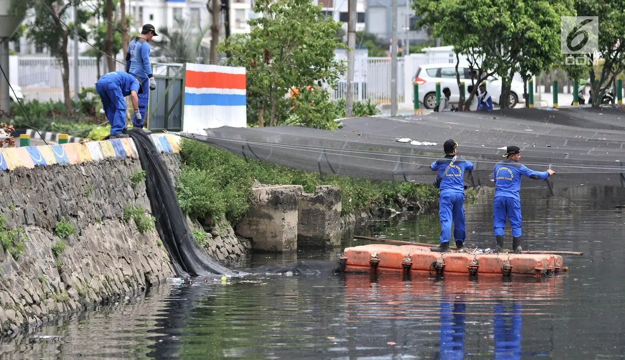 Petugas melepas kain waring atau jaring yang menutupi Kali Item di Kemayoran Jakarta, Rabu (14/11). Pelepasan waring yang sebagian dalam kondisi sudah robek itu dilakukan lantaran banyak warga yang membuang sampah di atasnya (Merdeka.com/Iqbal S. Nugroho)