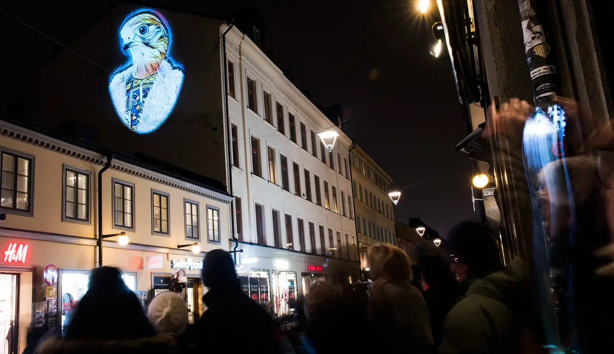 Sejumlah warga memperhatikan karya Julien Nonnon yang ditampilkan di sebuah bangunan di Sodermalm, Stockholm, Swedia (25/11). Pameran seni ini menggunakan sebuah teknik untuk memproyeksikan gambar pada permukaan datar. (AFP/Jonathan Nackstrand)