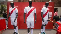 Seorang pengunjung mengabadikan jersey resmi timnas Peru untuk Piala Dunia 2018 di Rusia di Lima (18/12). Jersey ini mirip dengan desain sebelumnya yang dikenakan oleh atlet nasional selama Kualifikasi Amerika Selatan. (AFP Photo/Ernesto Benavides)