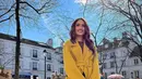 Tampilan modis Cinta Laura yang memadukan long coat warna mustard, burgundy top, celana panjang hitam, dan sepatu boots ini juga menarik untuk disontek. (Instagram/claurakiehl).