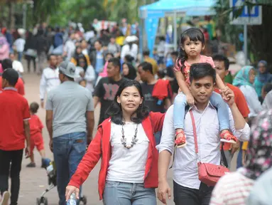 Seorang pengunjung menggendong anaknya saat berkunjung ke Ragunan, Jakarta, Minggu (25/12). Libur Natal dimanfaatkan warga untuk rekreasi bersama keluarga ke Ragunan. (Liputan6.com/Helmi Afandi)