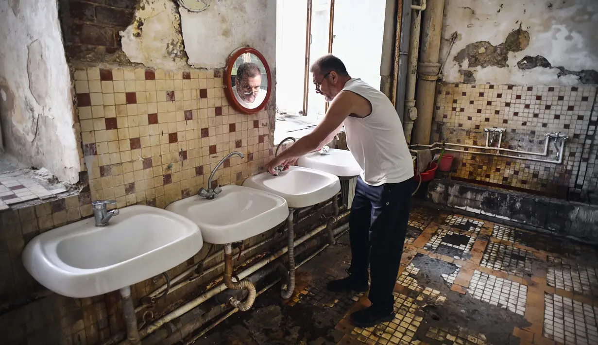 Vladimir Mogilnikov (62) mencuci tangannya di ruang cuci komunal asrama pekerja pabrik tekstil Proletarka di Kota Tver, Rusia, 8 Agustus 2020. Pabrik Tver yang terkenal dibuat oleh raja kapas Morozov pada abad ke-19 kini tidak ada lagi. (Alexander NEMENOV/AFP)