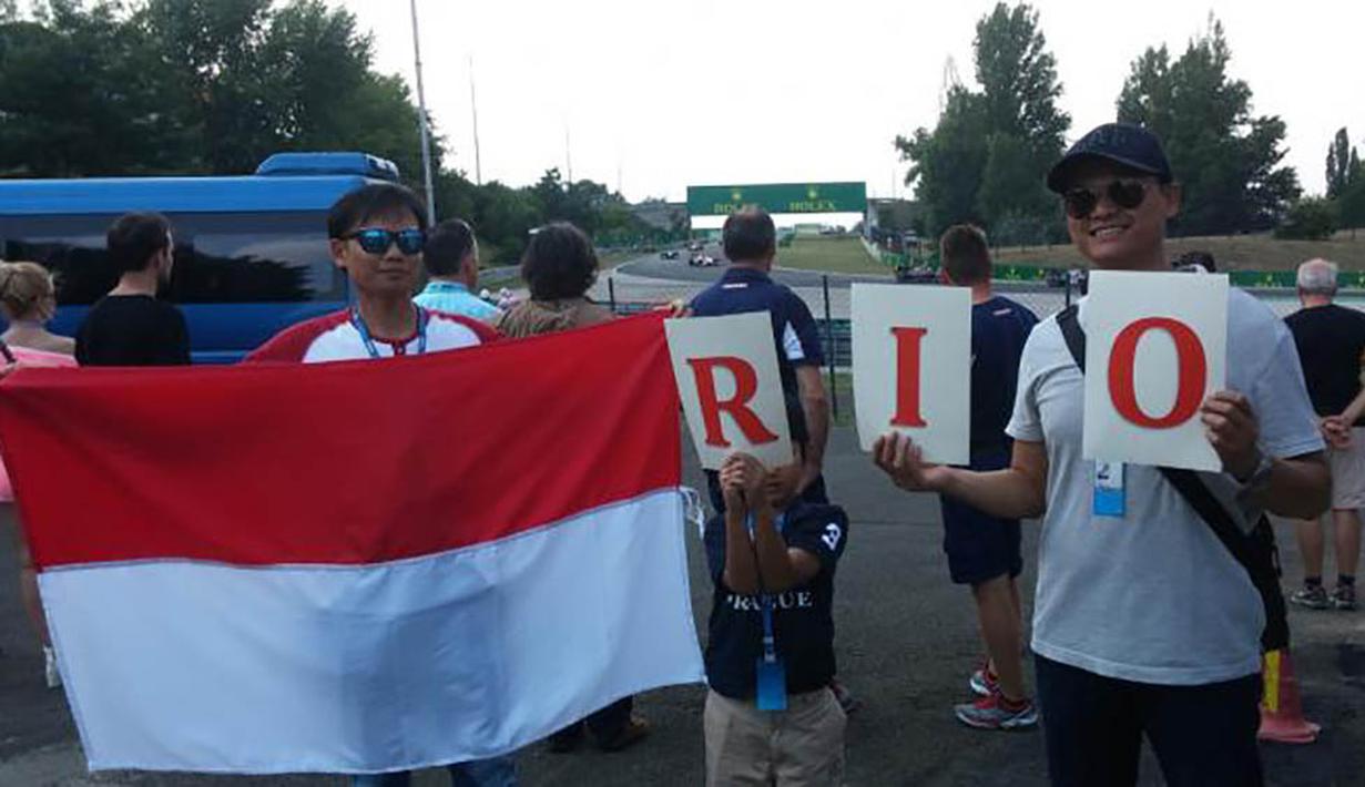 Warga Indonesia di Budapest, Hikmat Rijadi, bersama anak dan rekannya, Agus, memberikan dukungan untuk pebalap asal Indonesia, Rio Haryanto. (Bola.com/Reza Khomaini)