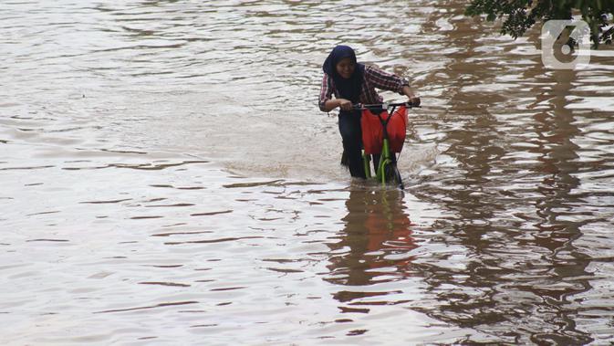 Warga menaiki sepeda menerobos genangan banjir di Jalan Gunung Sahari Jakarta, Selasa (25/2/2020). Hujan yang mengguyur Jakarta sejak Senin (24/2) malam membuat sejumlah kali meluap dan menyebabkan banjir. (Liputan6.com/Helmi Fithriansyah)