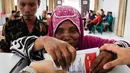 Seorang perempuan berkebutuhan khusus dibantu untuk memberikan suaranya di sebuah tempat pemungutan suara (TPS) di Medan, Sumatera Utara pada 14 Februari 2024. (Kartik BYMA/AFP)