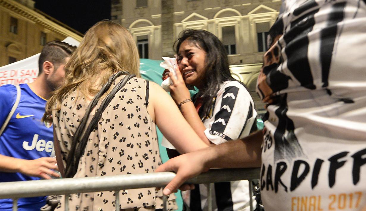 Seorang wanita menangis usai terjadi ledakan saat nonton bareng final Liga Champions di Piazza San Carlo, Turin, Sabtu (3/6/2017). Acara nobar dipadati sekitar 20.000 supporter Juventus. (AFP/Massimo Pinca)