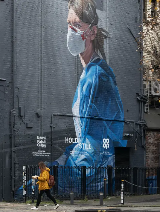 Seorang perempuan berjalan melewati mural perawat yang baru-baru ini dibuat di Manchester, Inggris, pada 5 November 2020. Inggris memasuki karantina wilayah (lockdown) selama sebulan mulai Kamis (5/11) untuk meredam merebaknya kembali penularan virus corona. (Xinhua/Jon Super)
