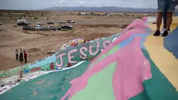 Turis mengunjungi Salvation Mountain, sebuah lereng bukti di Niland, California, Amerika Serikat. Dibangun dari kumpulan jerami, dempul jendela dan lebih dari 10,000 galon cat yang dipergunakan untuk membuat bukit tetap berdiri, dan melindunginya dari pasir dan angin gurun. (Robyn Beck/AFP)