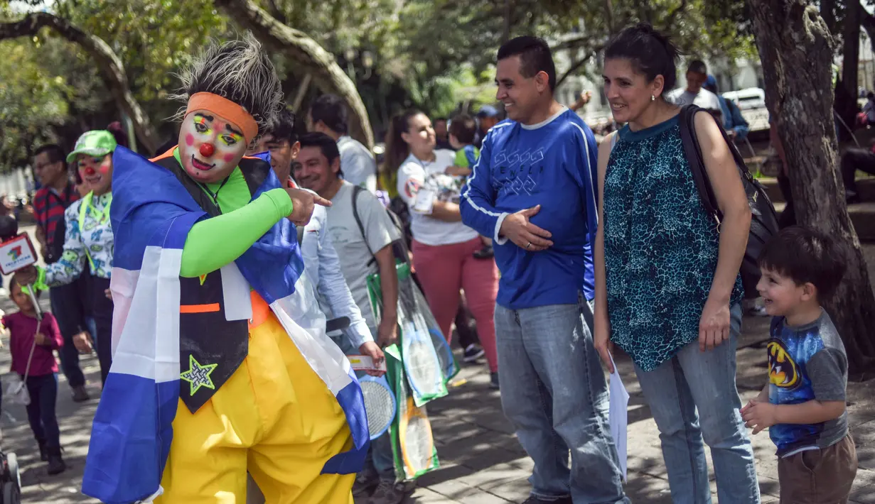 Seorang badut menghibur warga selama parade pada Konvensi Badut Regional ke-5 di kota Guatemala, Rabu (19/9). Dalam acara tersebut, dengan kostum warna-warninya mereka berparade menelusuri jalanan pusat sejarah Guatemala City. (AFP / Johan ORDONEZ)