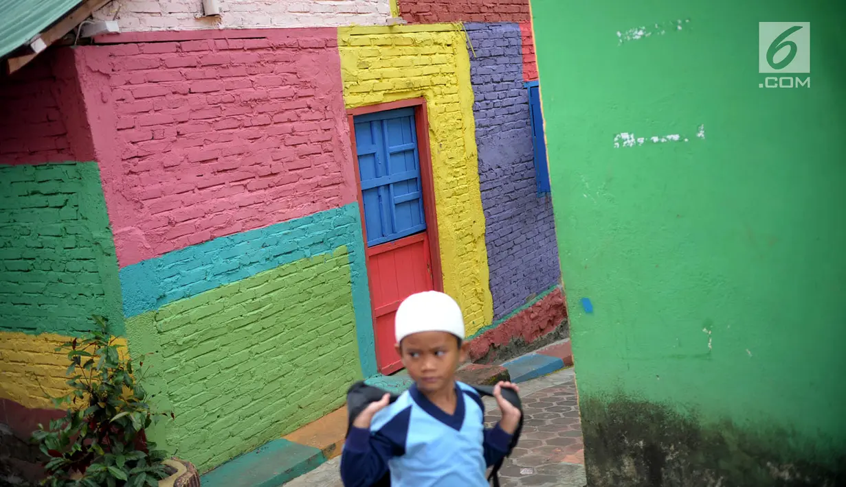Seorang bocah menyusuri jalan di Kampung Warna Warni Lubuklinggau, Sumatera Selatan, Rabu (10/1). Jika sebelumnya dikenal sebagai kampung kriminal, kini Kampung Warna Warni Lubuklinggau dikenal sebagai lokasi wisata. (Liputan6.com/Immanuel Antonius)
