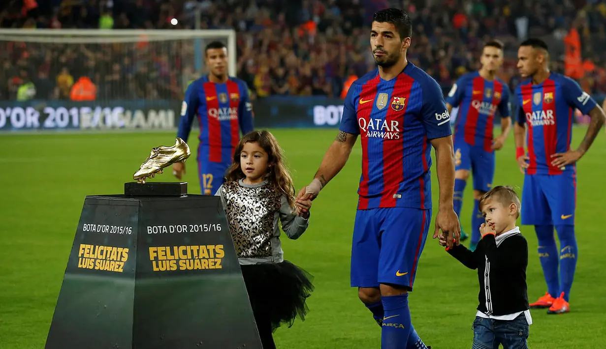 Striker Barcelona, Luis Suarez, didampingi anaknya saat menunjukan Sepatu Emas jelang laga La Liga melawan Granada di Stadion Nou Camp, Spanyol, Sabtu (29/10/2016). Suarez meraih gelar ini usai mencetak 40 gol pada musim lalu. (AFP/Lluis Gene)