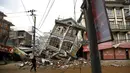 Foto yang diambil pada 1 Mei 2015 menunjukkan warga berjalan di dekat rumah yang runtuh setelah gempa 7,8 SR di Kathmandu. Setahun yang lalu, Nepal mengalami gempa terburuk dalam sejarah selama 80 tahun bencana di kawasan itu. (REUTERS/Navesh Chitrakar)