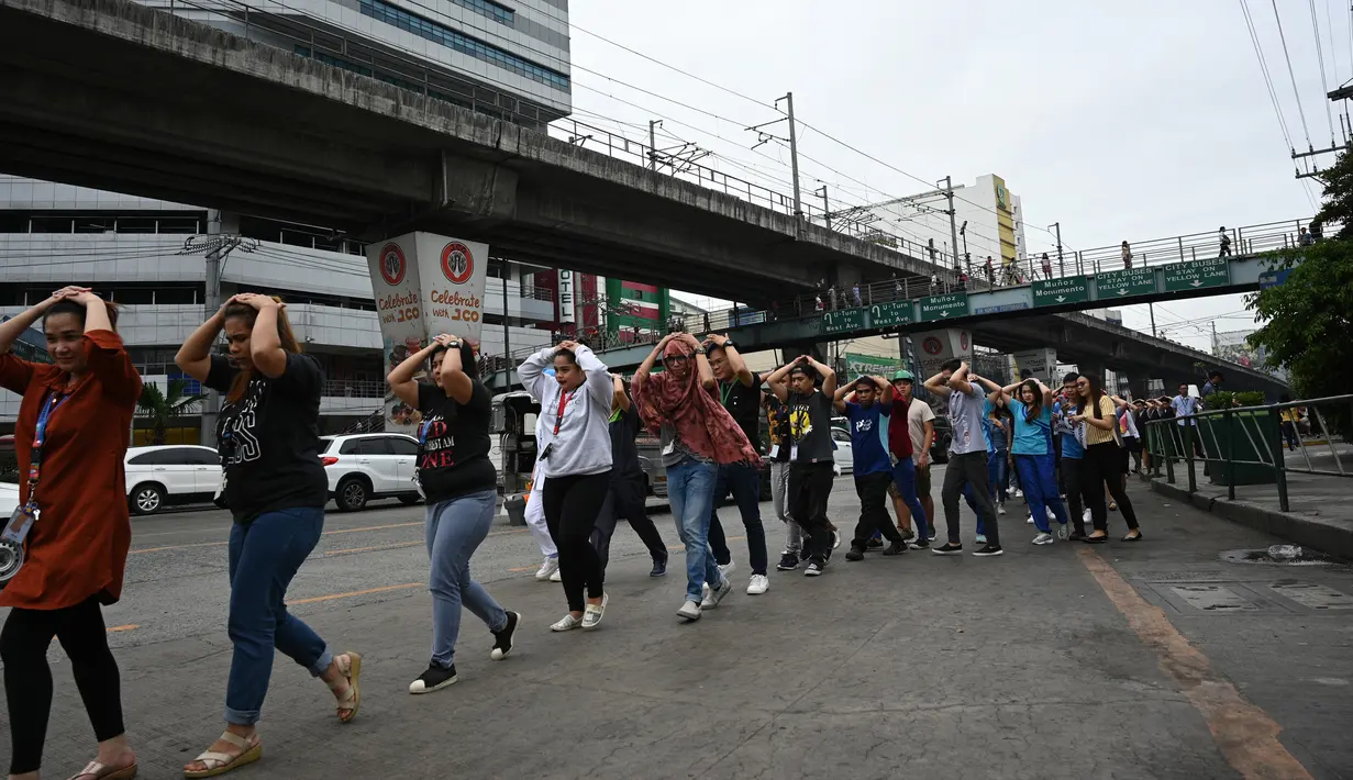 Karyawan call center melindungi kepalanya sambil berjalan saat mengikuti latihan gempa di Manila (14/11/2019). Latihan ini sebagai bagian dari kesiapsiagaan nasional menyusul berbagai gempa yang melanda pulau Mindanao bulan lalu. (AFP Photo/Ted Aljibe)