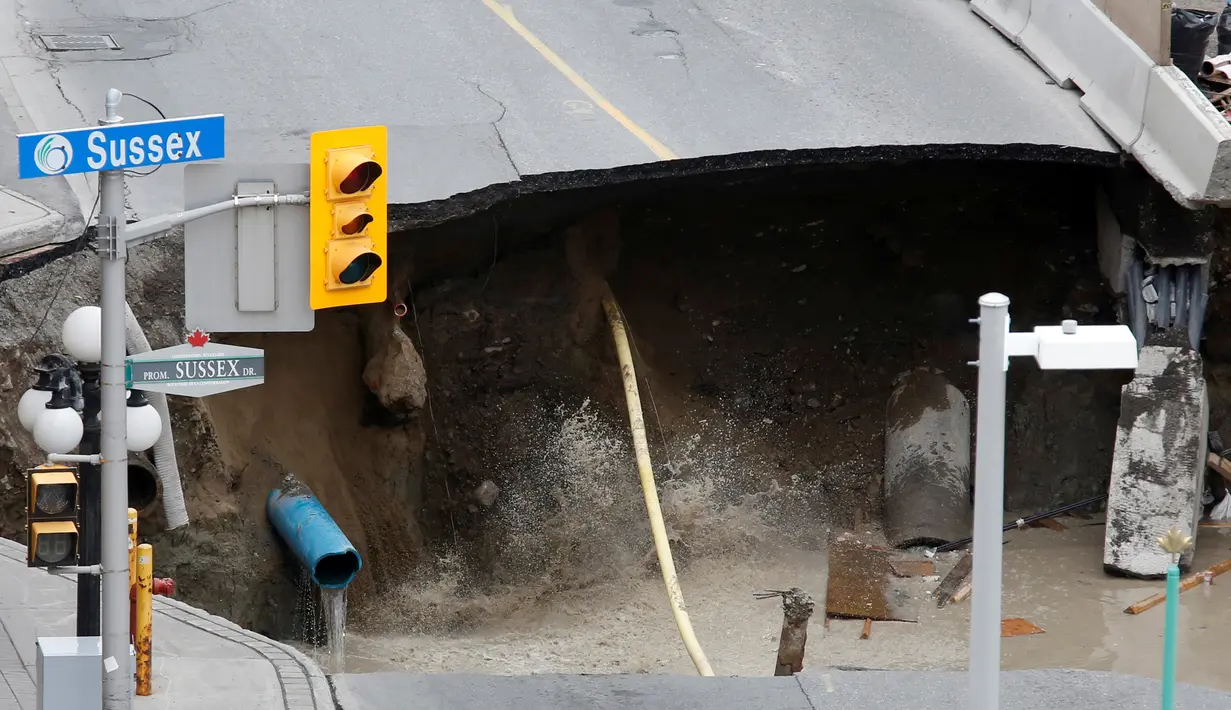 Penampakan sinkhole besar di Rideau Street, Ottawa, Kanada, Rabu (8/6). Lubang besar itu menyebabkan bocornya pipa gas dan penghuni di beberapa bangunan di jantung ibukota Kanada itu pun terpaksa dievakuasi. (REUTERS/Chris Wattie)