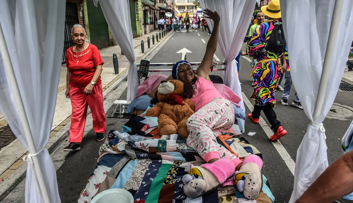 Seorang wanita Kolombia berbaring di tempat tidur saat ambil bagian dalam pawai merayakan Hari Kemalasan Sedunia di Itagui, dekat Medellin, Minggu (19/8). Upaya unik itu untuk medesak para perkerja yang tertekan agar bersantai. (AFP/JOAQUIN SARMIENTO)
