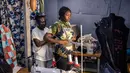 Seorang perancang busana menyesuaikan kreasi pada model amatir selama sesi fitting di sebuah studio mode di pemukiman informal Kibera di Nairobi, pada tanggal 20 September 2023 menjelang Kibera Fashion Week. (LUIS TATO/AFP)