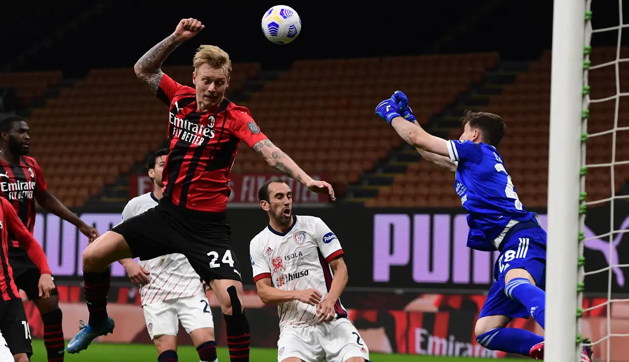 Kiper Cagliari, Alessio Cragno (kanan) membelokkan tembakan di bawah tekanan bek AC Milan, Simon Kjaer (kiri) pada pekan ke-37 Serie A di San Siro, Senin (17/5/2021) dini hari WIB.  AC Milan gagal menjauh di klasemen Liga Italia usai imbang 0-0 lawan Cagliari. (MIGUEL MEDINA / AFP)