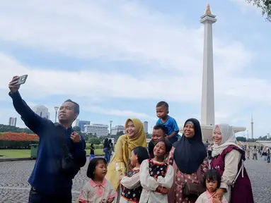 Warga berswafoto saat berwisata di kawasan Monumen Nasional (Monas), Jakarta, Sabtu (5/4/2025). (Liputan6.com/Herman Zakharia)